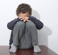 boy crying in poverty with no help crying alone and all by himself on white background stock photo